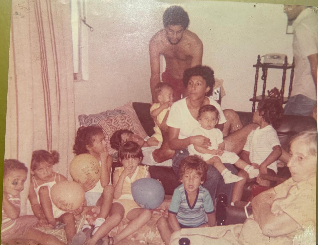 Fotografia antiga de família reunida em casa, com crianças — registro das raízes da família Carlota.